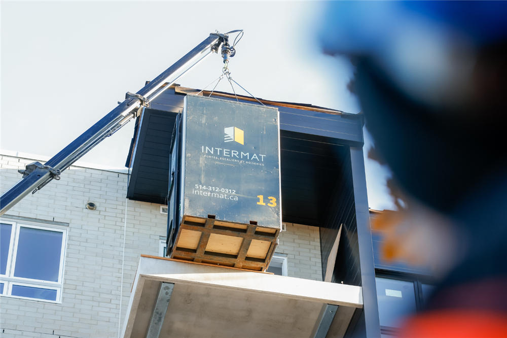 Livraison de matériaux de finition intérieure sur un chantier par Intermat, avec levage d’une palette de portes intérieures à l’aide d’une grue, illustrant la gestion de chantier et la prévention des retards de livraison chantier.